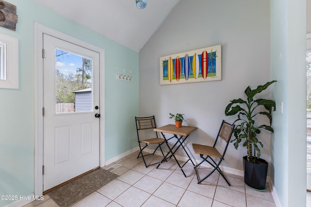 entrance foyer featuring vaulted ceiling, light tile patterned floors, and baseboards