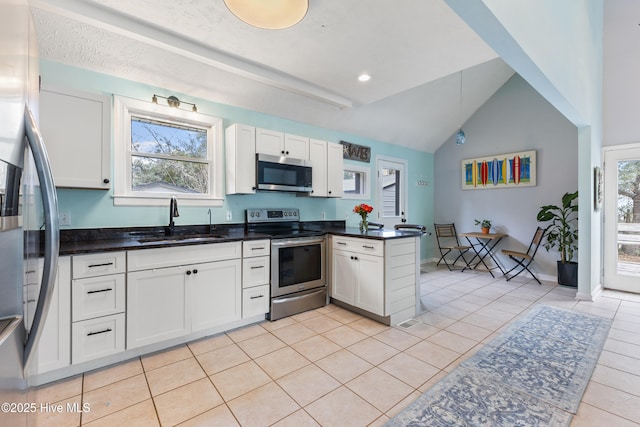 kitchen with a wealth of natural light, white cabinets, appliances with stainless steel finishes, and a sink