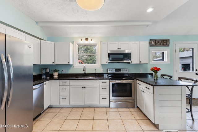 kitchen featuring a kitchen bar, a peninsula, white cabinets, stainless steel appliances, and a sink