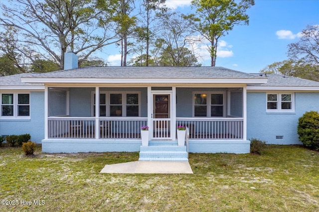 ranch-style home with brick siding, a front lawn, covered porch, a chimney, and crawl space