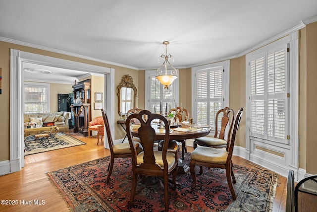 dining area featuring light wood-style flooring, crown molding, and baseboards