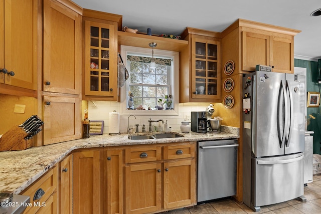 kitchen featuring a sink, light stone countertops, backsplash, and stainless steel appliances