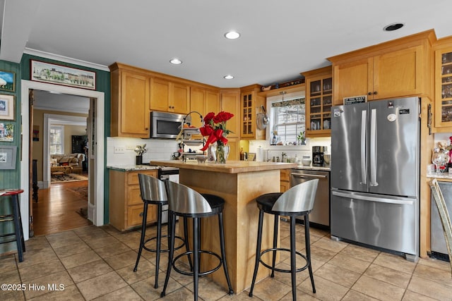 kitchen with a kitchen breakfast bar, a center island, appliances with stainless steel finishes, light countertops, and decorative backsplash