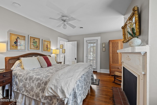 bedroom featuring dark wood finished floors, a fireplace with flush hearth, ceiling fan, and baseboards