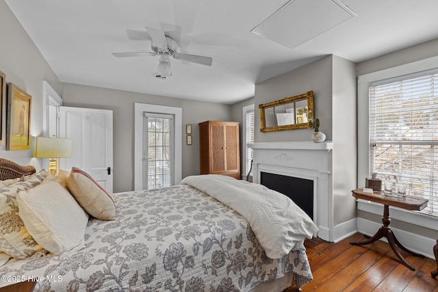 bedroom featuring ceiling fan, a fireplace, baseboards, and wood-type flooring