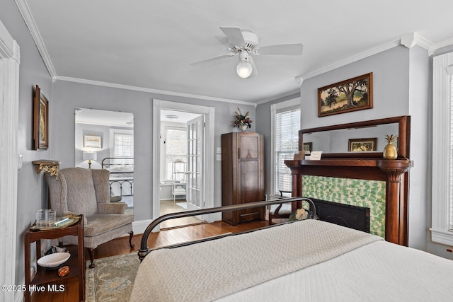 bedroom with a ceiling fan, wood finished floors, ornamental molding, and a tile fireplace