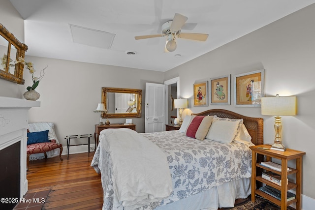 bedroom featuring visible vents, attic access, hardwood / wood-style floors, a fireplace, and a ceiling fan