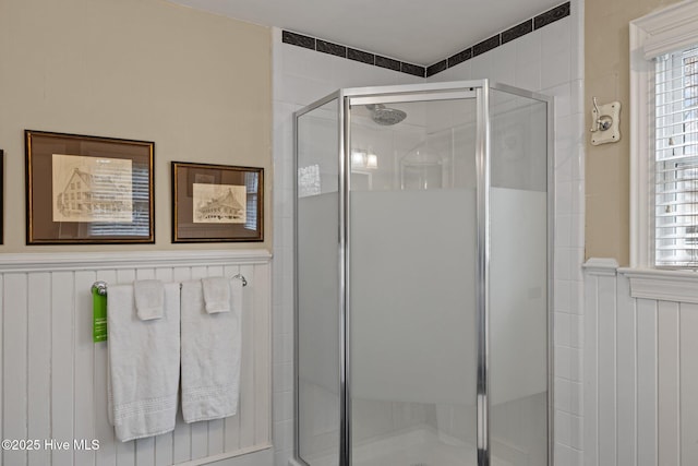 full bathroom featuring wainscoting and a shower stall