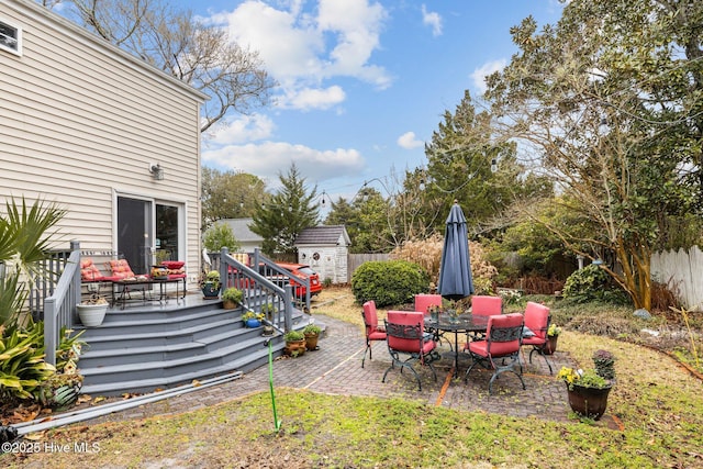 view of yard featuring an outbuilding, fence, a storage unit, a deck, and a patio area