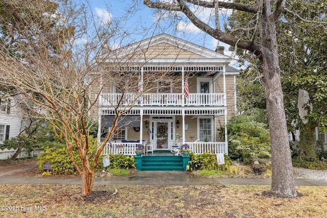 view of front facade with a porch, a chimney, and a balcony