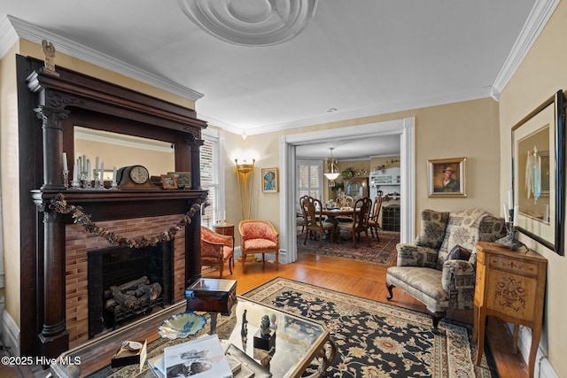 living room with a brick fireplace, wood finished floors, and ornamental molding