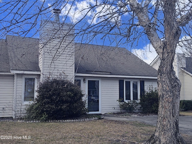 new england style home featuring a shingled roof and a chimney