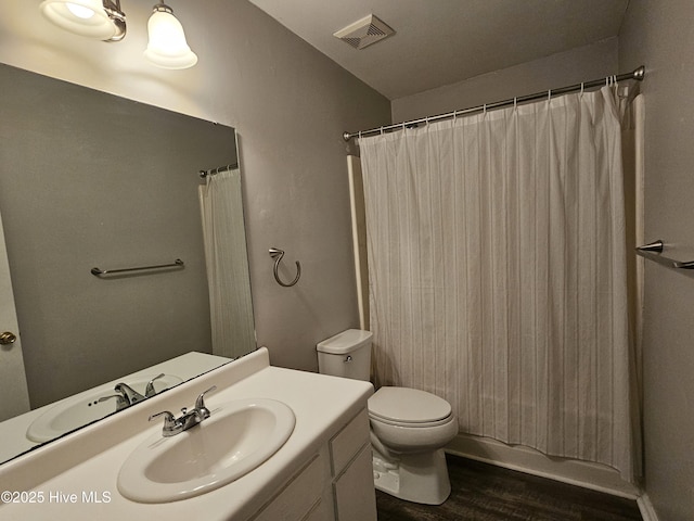 bathroom featuring toilet, visible vents, wood finished floors, and vanity