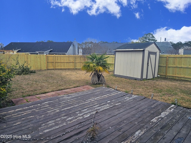 wooden deck with a fenced backyard, a shed, and an outbuilding