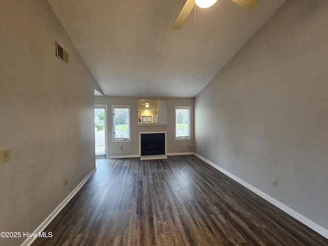 unfurnished living room featuring baseboards, visible vents, dark wood finished floors, a ceiling fan, and a fireplace