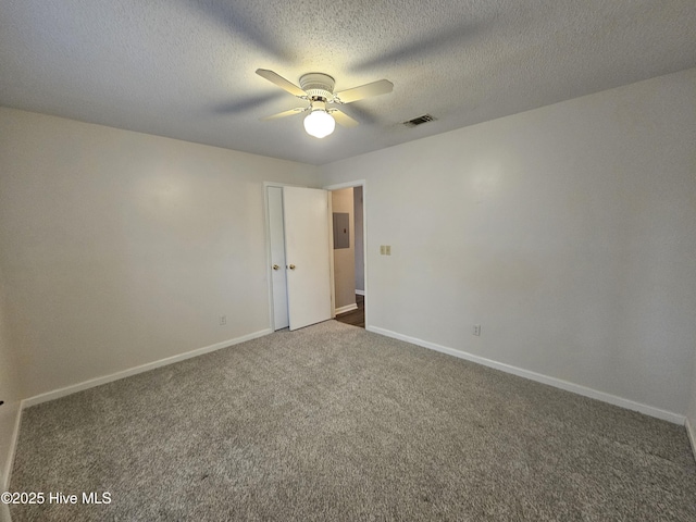 empty room with electric panel, baseboards, visible vents, a ceiling fan, and carpet floors