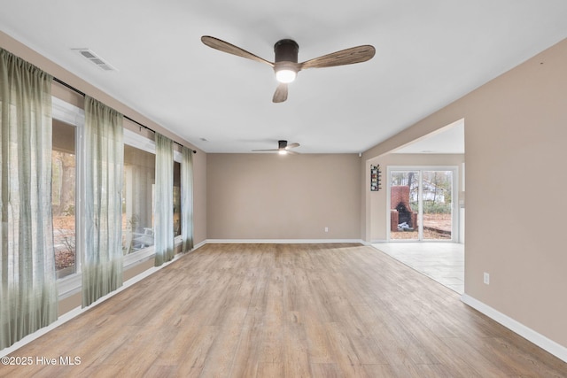 spare room featuring light wood-style floors, baseboards, visible vents, and ceiling fan