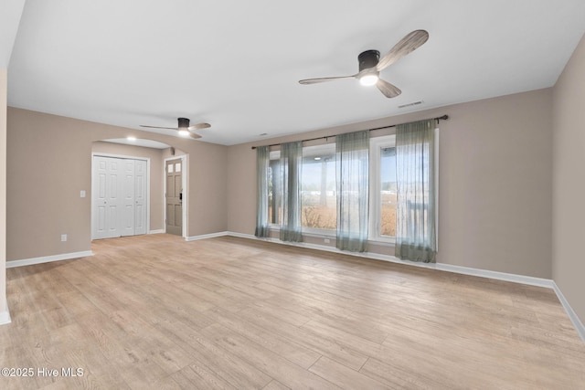 unfurnished room featuring arched walkways, visible vents, a ceiling fan, and light wood-style floors