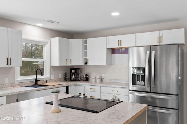 kitchen with white cabinets, visible vents, stainless steel refrigerator with ice dispenser, and a sink