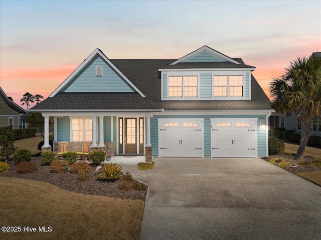 view of front of house featuring a shingled roof, covered porch, driveway, and an attached garage