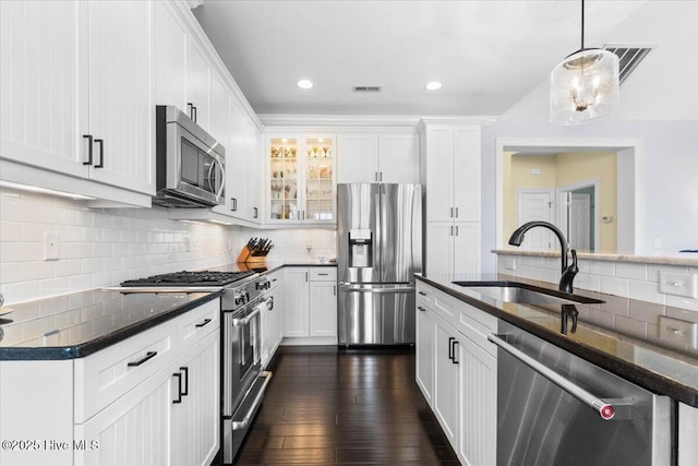 kitchen with stainless steel appliances, a sink, white cabinetry, and decorative backsplash