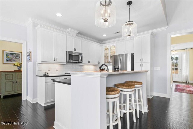 kitchen featuring stainless steel appliances, dark wood-style flooring, white cabinets, and decorative backsplash