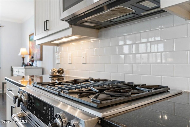 interior space featuring tasteful backsplash, stainless steel gas range, white cabinets, and ventilation hood