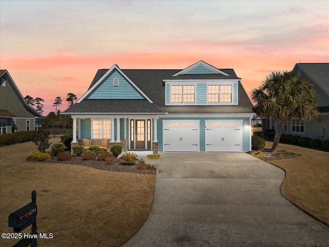 view of front of property with driveway, a garage, a front lawn, and a porch