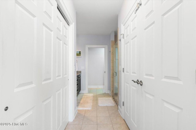 hallway featuring light tile patterned floors and baseboards