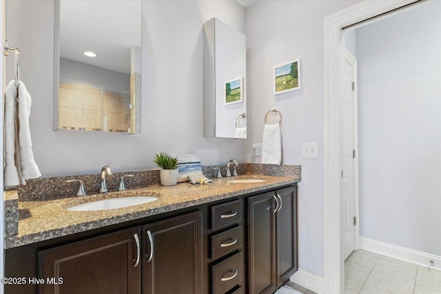 full bathroom with double vanity, baseboards, a sink, and tile patterned floors