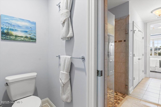 bathroom with toilet, a shower stall, baseboards, and tile patterned flooring