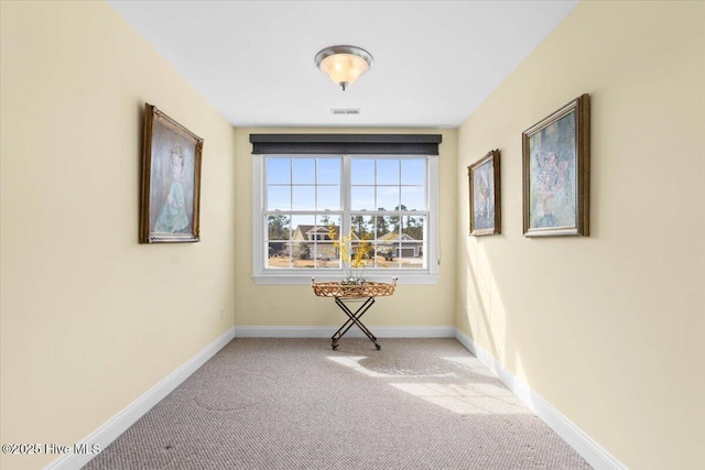 empty room featuring baseboards, visible vents, and light colored carpet