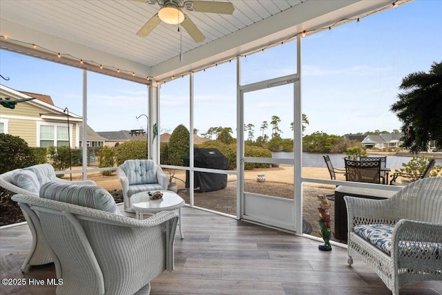 sunroom / solarium featuring a ceiling fan and a water view