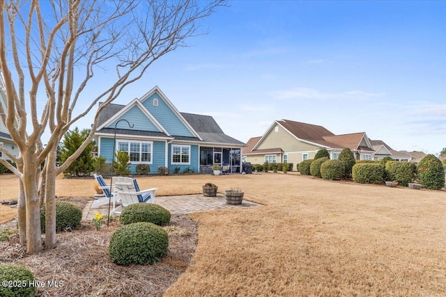 view of front of house featuring a front yard, a sunroom, a patio, and a fire pit