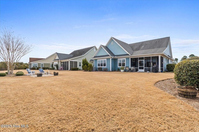 back of property with a sunroom, a patio area, and a lawn