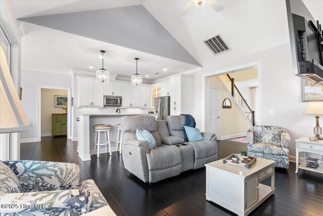 living area with ceiling fan, stairway, dark wood finished floors, and visible vents