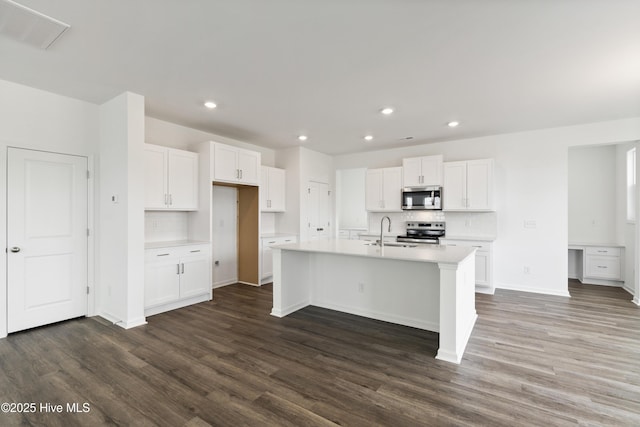 kitchen with a sink, dark wood-type flooring, appliances with stainless steel finishes, and white cabinets
