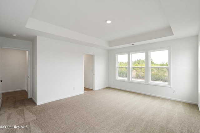 empty room featuring carpet flooring, baseboards, and a tray ceiling