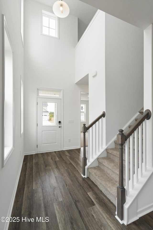 entryway with baseboards, a high ceiling, dark wood finished floors, and stairs