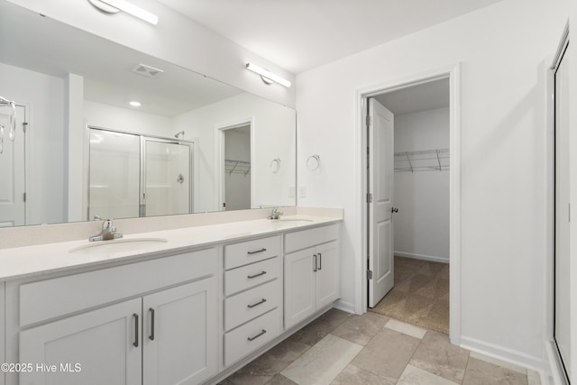 full bath with double vanity, visible vents, a shower stall, and a sink