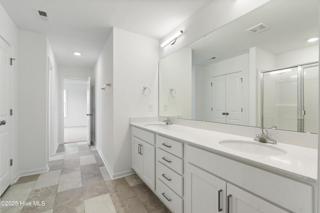 full bathroom featuring double vanity, visible vents, a shower stall, and a sink
