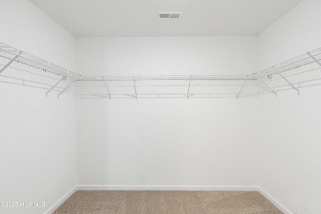 walk in closet featuring visible vents and light carpet