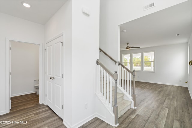 stairs with a ceiling fan, wood finished floors, visible vents, and baseboards