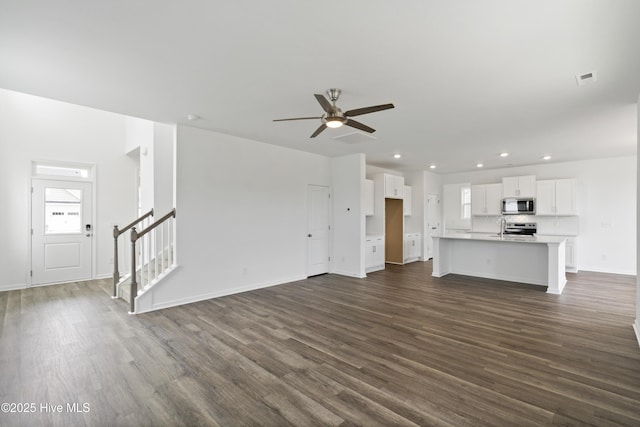 unfurnished living room with baseboards, ceiling fan, stairs, recessed lighting, and dark wood-style flooring