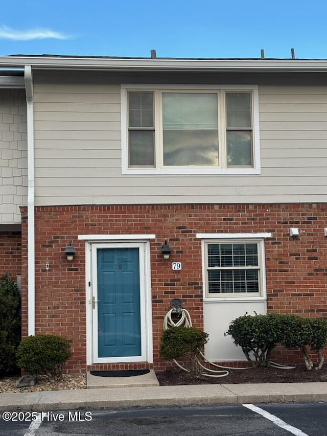 property entrance featuring uncovered parking and brick siding