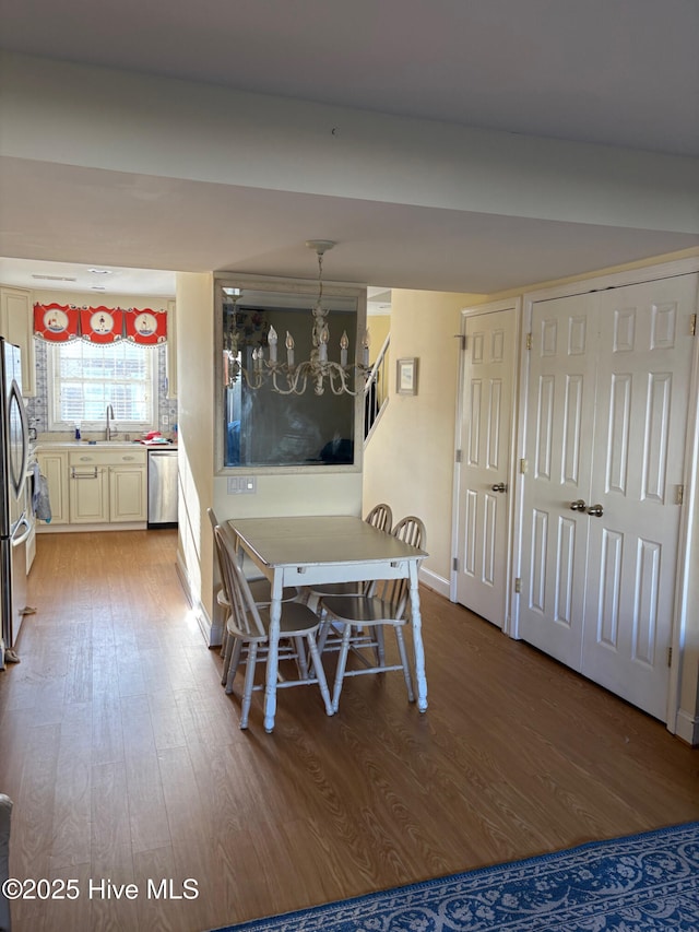 unfurnished dining area with a sink, a chandelier, and wood finished floors