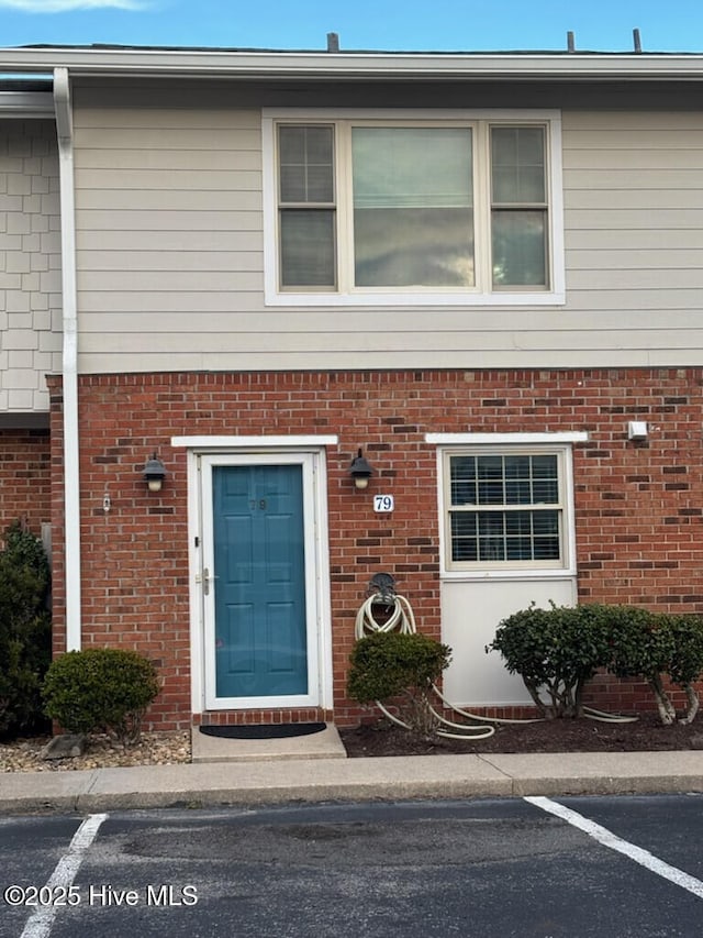 property entrance with uncovered parking and brick siding