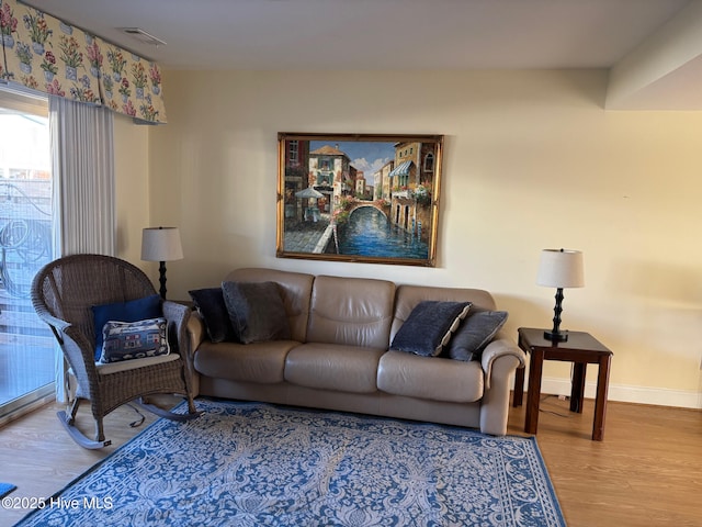 living area featuring baseboards, visible vents, and wood finished floors