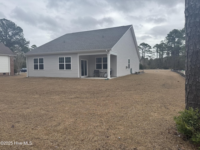 rear view of house with a shingled roof and a patio