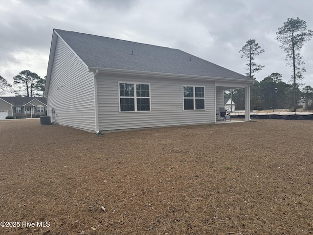 rear view of property with central air condition unit, a shingled roof, and a patio